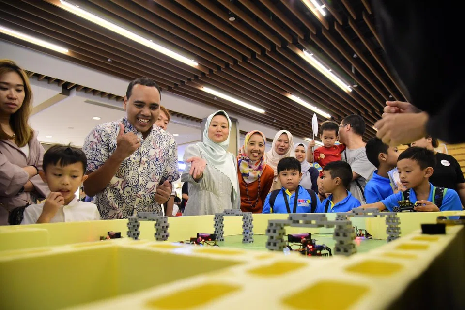 SERONOK MENCUBA: Anggota Parlimen GRC Chua Chu Kang, Encik Zhulkarnain Abdul Rahim (dua dari kiri) dan Setiausaha Parlimen Kanan (Kesihatan merangkap Undang-undang), Cik Rahayu Mahzam (tiga dari kiri)  menyertai kanak-kanak yang mencuba kegiatan di Trek Lumba dan Balapan Berhalang di acara Raikan Ilmu@Heartlands (Jurong East) di IMM pada Sabtu.
