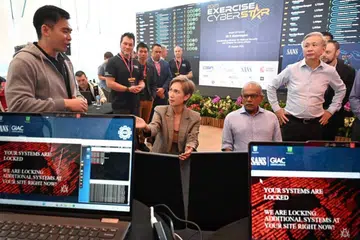 (Duduk, dari kiri) Menteri Pembangunan Digital dan Penerangan Cik Josephine Teo dan Menteri Penyelaras Keselamatan Negara Encik K. Shanmugam meninjau pameran di Exercise Cyber Star pada 1 Ogos 2025.