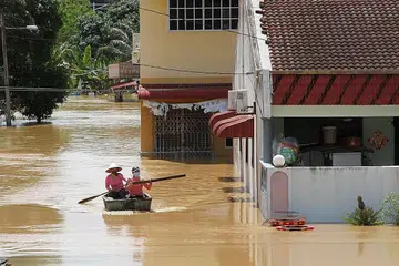 CARI TEMPAT SELAMAT: Dua penduduk di daerah Segamat, Johor, dilihat sedang menaiki bot di kawasan banjir selepas sebahagian daerah itu ditenggelami banjir selepas hujan lebat berterusan. - Foto THE STAR