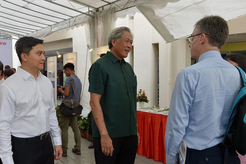 PAMERAN MEMPERINGATI PENGASAS: Encik Saktiandi (kiri) dan Dr Ng (tengah) berinteraksi dengan penduduk yang hadir di pameran peringatan sempena setahun pemergian mendiang Encik Lee di Kelab Masyarakat Toa Payoh Central semalam. - Foto TUKIMAN WARJI