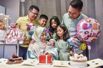 SAMBUT EMPAT HARI LAHIR SEKALI GUS: Dr Jazlan Joosoph (kiri) sama-sama meraikan hari lahir anak-anak Encik Salihin Ahmad Perbah (kanan) dan Cik Khairunnisa Abdul Karim (duduk sambil menggendong bayi).