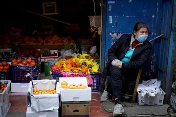 CABARAN DUNIA: Seorang wanita memakai pelitup duduk di sebelah gerai menjual buah-buahan di kawasan kejiranan selepas sekatan berkurung ditarik balik di Wuhan, ibu kota wilayah Hubei dan merupakan pusat penularan penyakit koronavirus.