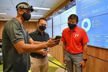 TINGKATKAN PEKERJA: (Dari kiri) Seorang teknisyen Schindler Lifts, Encik Abdul Razak Abd Rahman, menunjukkan Encik Zaqy dan Encik Ng Chee Meng, Setiausaha Agung NTUC, sebuah aplikasi yang membantu dalam tugasannya. - Foto BH oleh CHONG JUN LIANG