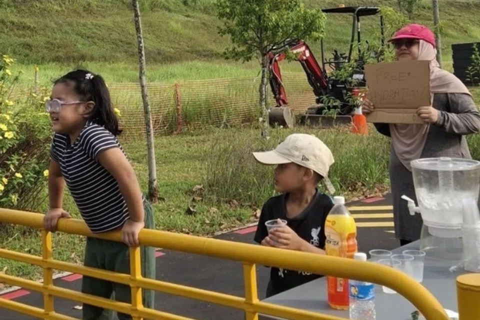 Cik Izyan (kanan) bersama anak-anaknya semasa pengagihan minuman isotonik pada 26 September sepanjang Woodlands Avenue 12.