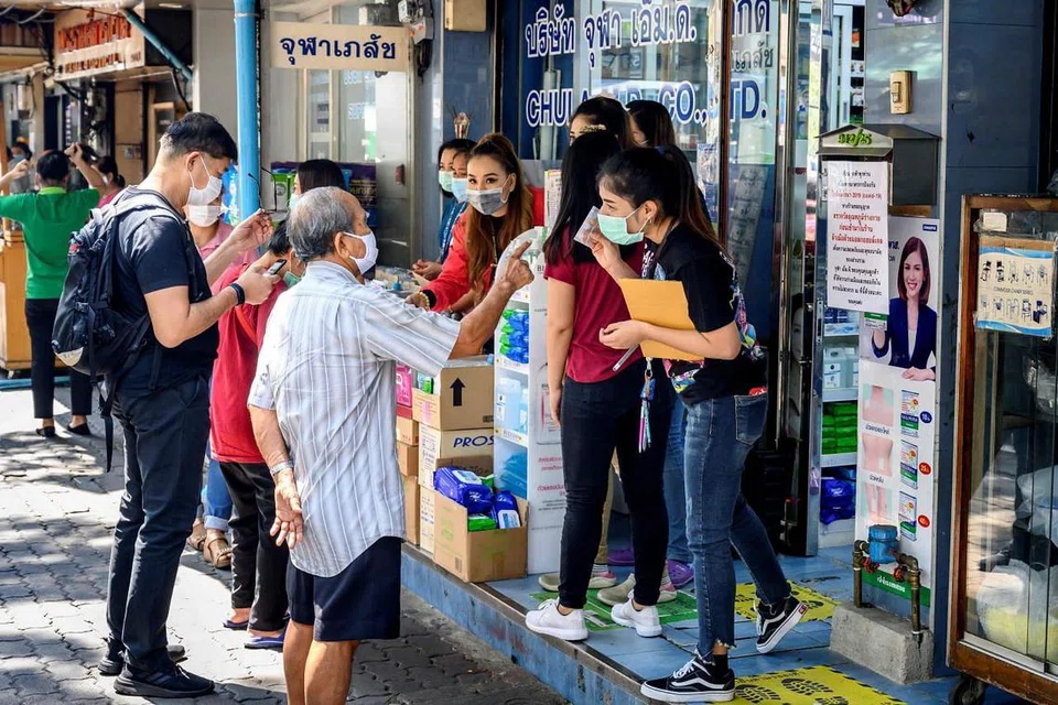 BERSIAP SEDIA: Beberapa orang dilihat sedang membeli barang keperluan seperti pensanitasi tangan di sebuah farmasi di Bangkok pada 28 April 2020. - FOTO: AFP.
