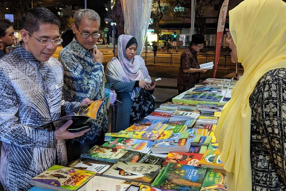 PESTA BUKU DAPAT SAMBUTAN: Dr Maliki (di kiri dalam gambar atas) meninjau pelbagai buku Melayu dan dwibahasa karya penulis tempatan dalam Pesta Buku Melayu Singapura 2019. Para hadirin juga diperkenalkan dengan pelbagai buku Melayu. - Foto WGS.