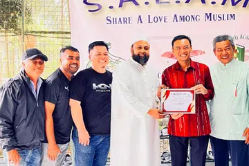 Pengasas Al Falah Academy SG (AFASG), Ustaz Muhammad Ferozudeen Al Hafiz (tiga dari kanan, berjubah putih), bersama Anggota Parlimen (AP) GRC Jalan Besar, Dr Wan Rizal Wan Zakariah (dua dari kanan), dalam projek SALAM di mana AFASG bekerjasama dengan Masjid Omar Salmah bagi mengagihkan daging korban kepada penerima berkelayakan di Singapura pada 2023. 