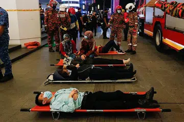 TUNGGU DIBAWA KE HOSPITAL: Beberapa penumpang yang cedera dibaringkan di atas tandu di luar stesen KLCC selepas kemalangan yang melibatkan dua tren LRT di Kuala Lumpur malam kelmarin. - Foto AFP