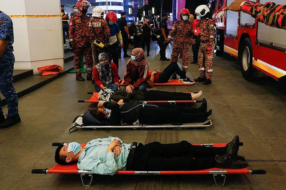 TUNGGU DIBAWA KE HOSPITAL: Beberapa penumpang yang cedera dibaringkan di atas tandu di luar stesen KLCC selepas kemalangan yang melibatkan dua tren LRT di Kuala Lumpur malam kelmarin. - Foto AFP