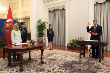 UPACARA RASMI: Presiden Halimah Yacob (kiri) telah merasmikan pelantikan hakim kanan, Encik Tan Siong Thye Lawrence (kanan), sebagai hakim kanan Mahkamah Agung Singapura.