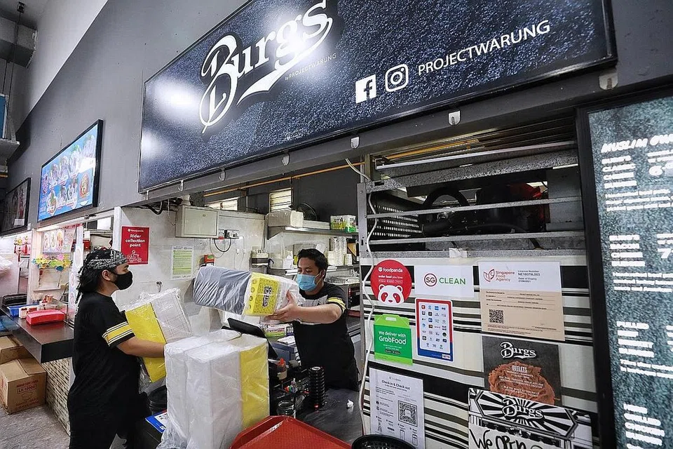 BUAT PERSEDIAAN: Kakitangan Burgs by Project Warung di cawangan Punggol menyediakan kotak-kotak pembungkusan bagi persediaan tempahan bermula hari ini. Dek langkah pengurusan selamat yang diperketat, orang ramai tidak lagi dibenarkan makan di luar, hanya tempahan makanan dibenarkan. - Foto BM oleh KEVIN LIM