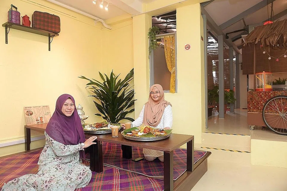 KONSEP ALA KAMPUNG: Pemilik bersama Hajjah Mariam Cafe, Cik Adhana Kamis (kanan) dan Cik Azidah Kamis, berkata cawangan terbaru mereka di North Bridge Road menyediakan suasana kampung dengan pelanggan boleh duduk makan bersila di atas tikar mengkuang. Ini adalah sebahagian usaha mereka untuk memperkenalkan dan melestarikan budaya Melayu. - Foto BH oleh ALPHONSUS CHERN