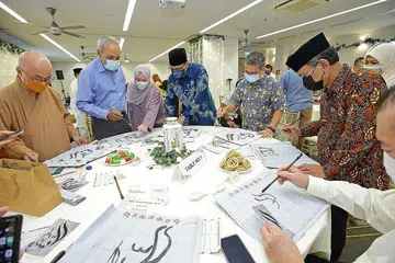 HUBUNGAN ERAT: Menteri Kebudayaan, Masyarakat dan Belia merangkap Menteri Kedua Undang-Undang, Encik Edwin Tong (lima dari kiri), kelihatan sedang melakukan aktiviti tulisan kaligrafi Islam Cina semasa majlis Perjumpaan Hari Raya antara agama bersama Ketua Eksekutif Majlis Ugama Islam Singapura (Muis), Encik Kadir Maideen (empat dari kiri) dan Presiden Muis, Encik Saat A. Rahman (dua dari kanan). - Foto MUIS
