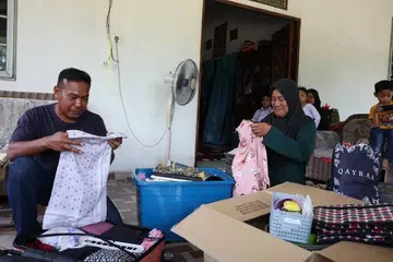 Cik Norinda Kasim (kanan) dan suaminya tidak dapat menahan sebak apabila hanya mampu melihat baju kepunyaan Allahyarhamha Nur Dalila Farhana Mohamad Isma, selepas anaknya sulungnya itu maut dalam kemalangan melibatkan bas di Jalan Raya Timur-Barat (JRTB) berhampiran Tasik Banding, Gerik di Perak pada 9 Jun.