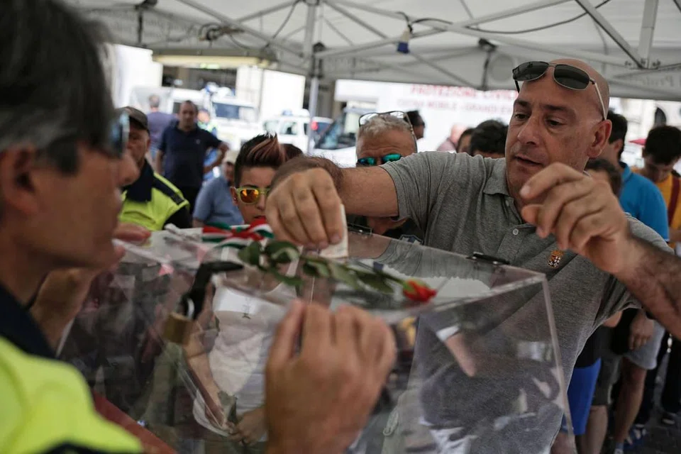 HULUR DERMA: Orang ramai menghulurkan derma bagi mangsa gempa dalam sebuah majlis amal di Piazza San Carlo di Turin kelmarin. Gempa sekuat 6.2 magnitud telah melanda tiga bandar di Italy dan membunuh 290 penduduk. - Foto AFP