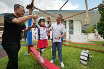 Encik Edwin Tong (kanan) dan Pengarah Eksekutif Musim Mas Holdings, Encik Alvin Lim (kiri) sedang membantu seorang pelajar mengharungi laluan halangan yang merupakan sebahagian daripada pembelajaran luar PCF Sparkletots @ Joo Chiat. 