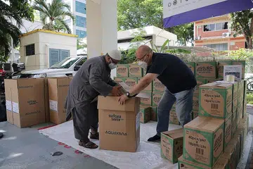 BANTUAN KEMANUSIAAN KRISIS DI GAZA: Ustaz Muslim Ahmad (kiri) dan Encik Dennis Khoo antara relawan yang turun padang menyiapkan bekalan bagi bantuan kemanusiaan di Gaza semalam. - Foto BH oleh GIN TAY