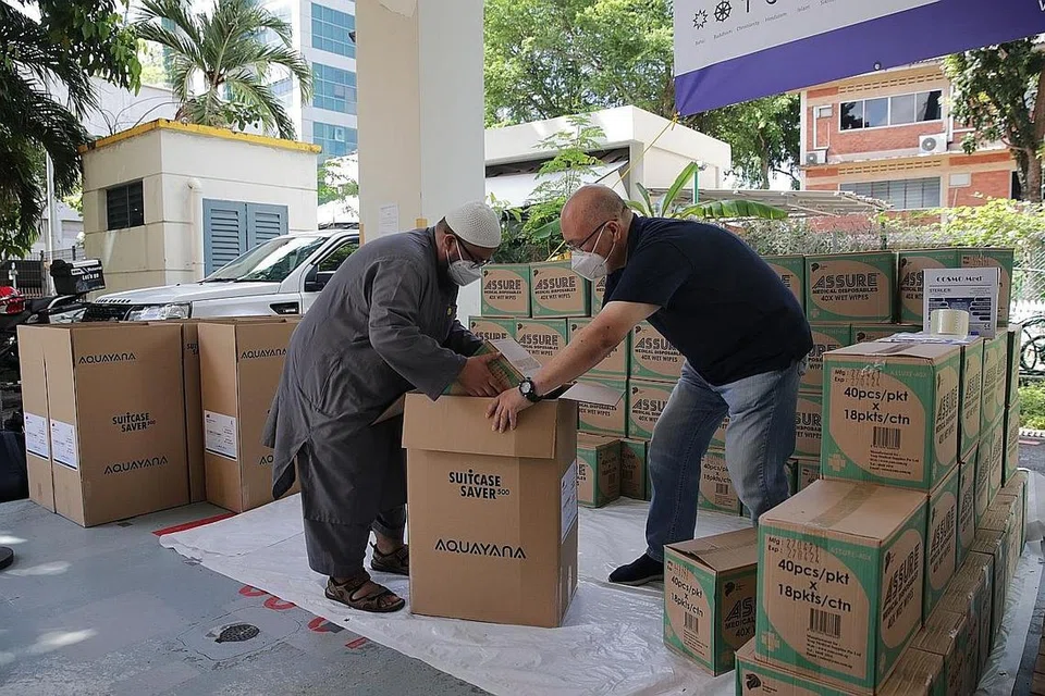 BANTUAN KEMANUSIAAN KRISIS DI GAZA: Ustaz Muslim Ahmad (kiri) dan Encik Dennis Khoo antara relawan yang turun padang menyiapkan bekalan bagi bantuan kemanusiaan di Gaza semalam. - Foto BH oleh GIN TAY