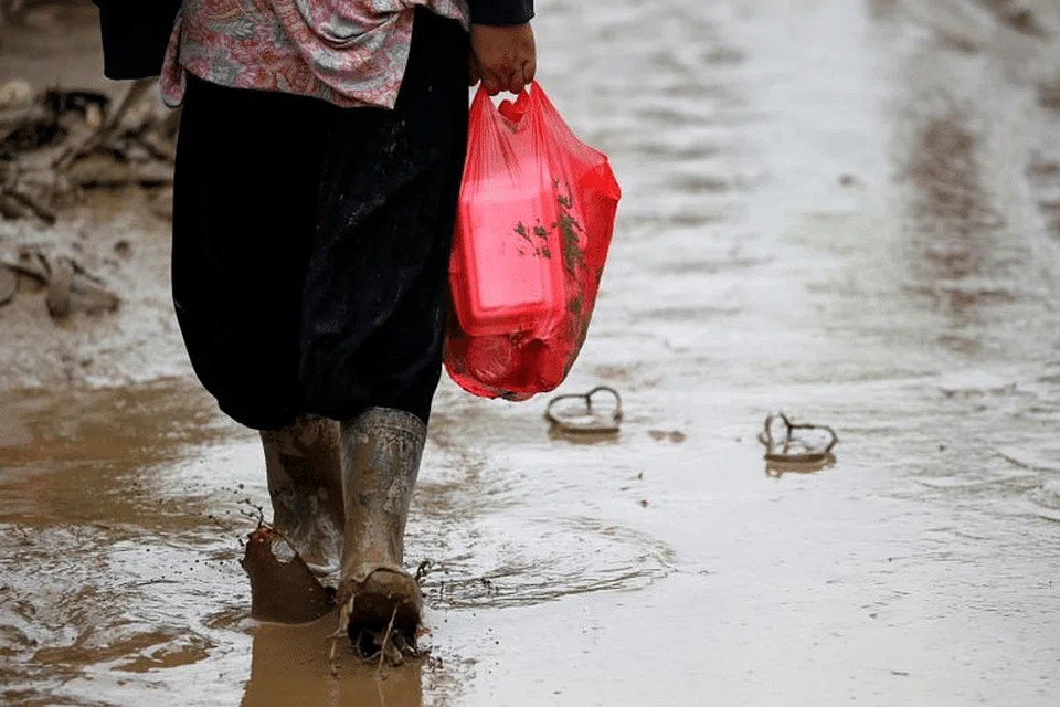 Seorang wanita membawa beg plastik mengandungi makanan di Bekasi, wilayah Jawa Timur, Indonesia. - Foto REUTERS 