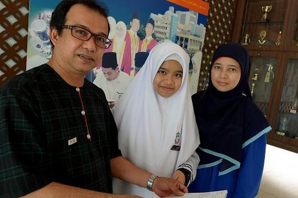 KONGSI KEGEMBIRAAN: Nur Masyitah mengongsi kegembiraan dan kesyukuran di atas kejayaannya bersama bapanya, Encik Borhan, dan ibunya, Cik Junaidah. - Foto TUKIMAN WARJI