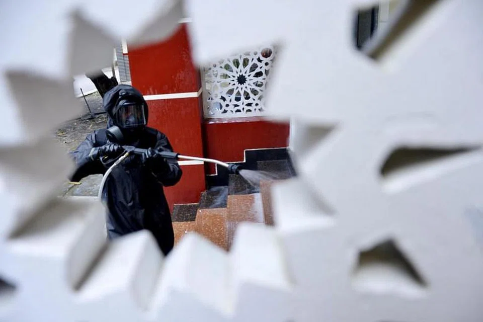 BASMI KUMAN: Seorang pegawai yang memakai sut perlindungan menyembur bahan basmi kuman di sebuah masjid di Makassar, Indonesia pada 16 Mac 2020. 