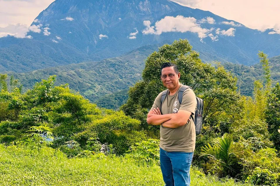 Encik Sahari merakam gambar dengan latar belakang Gunung Kinabalu.