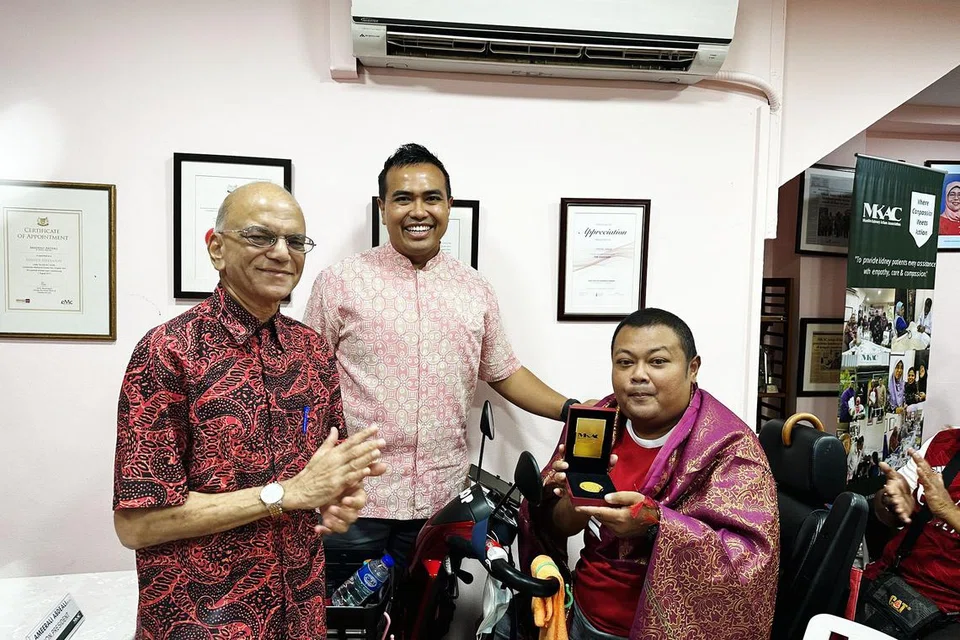 BANTU PESAKIT GINJAL LAIN: Encik Mohd Kamsani AB Hamed (kanan), menerima Anugerah Ketabahan MKAC daripada Anggota Parlimen (AP) Pasir Ris–Punggol, Encik Sharael Taha (tengah), dan Presiden Kehormat MKAC, Encik Ameerali Abdeali (kiri), atas sumbangnnya mengedarkan makanan dan menjadi sumber inspirasi buat pesakit ginjal lain.