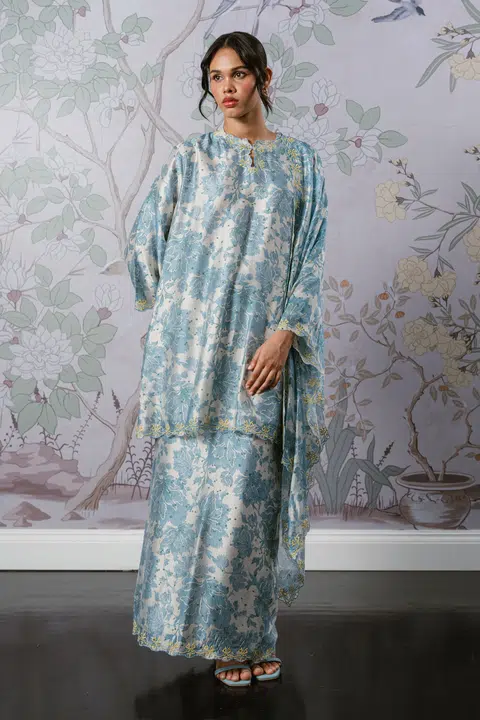 Set kurung Serene dengan selendang berwarna karang biru ($140) menawarkan potongan longgar dengan gaya potongan bahu menurun (drop shoulder) dan skirt pensel yang memberi ilusi tubuh langsing.