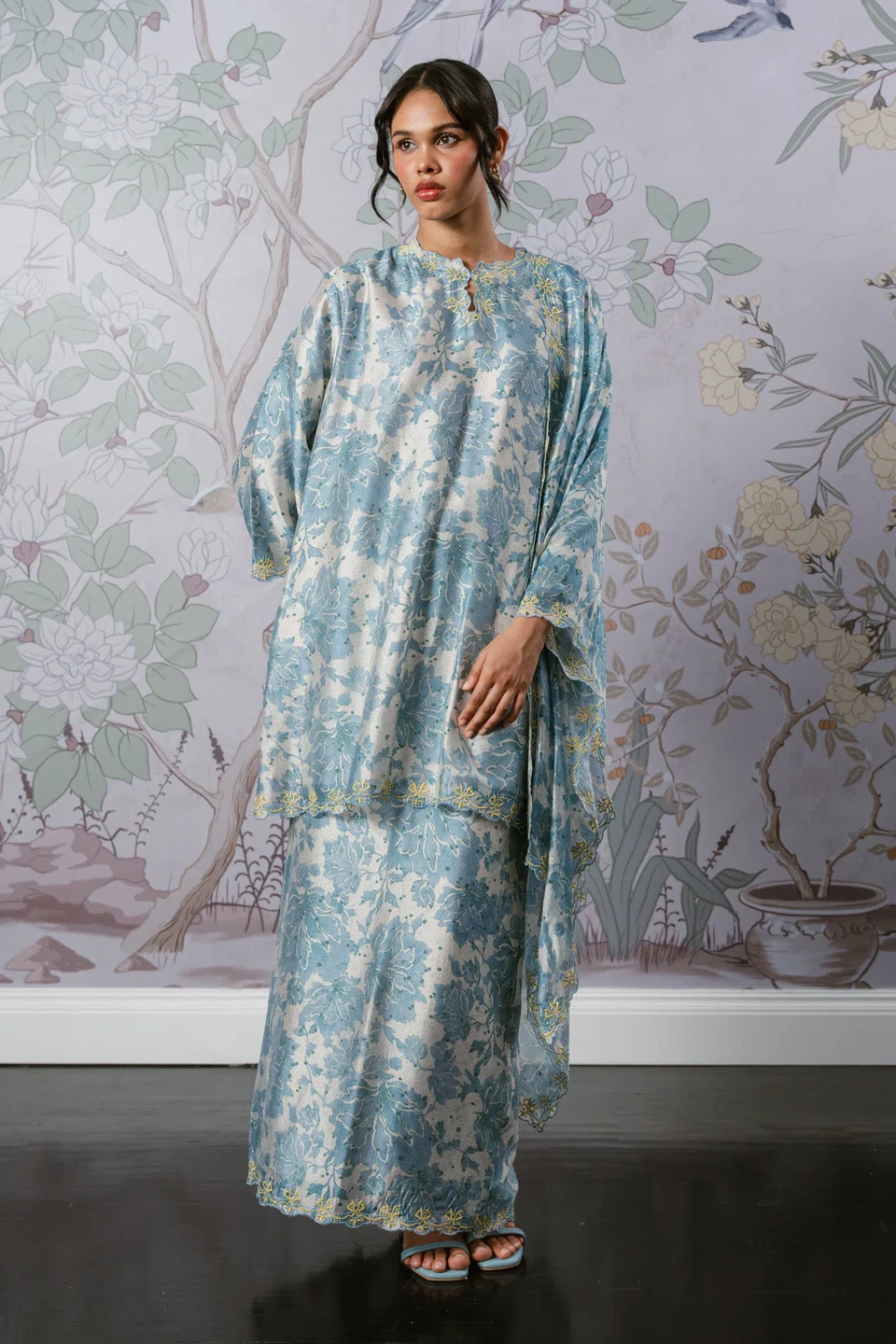Set kurung Serene dengan selendang berwarna karang biru ($140) menawarkan potongan longgar dengan gaya potongan bahu menurun (drop shoulder) dan skirt pensel yang memberi ilusi tubuh langsing.