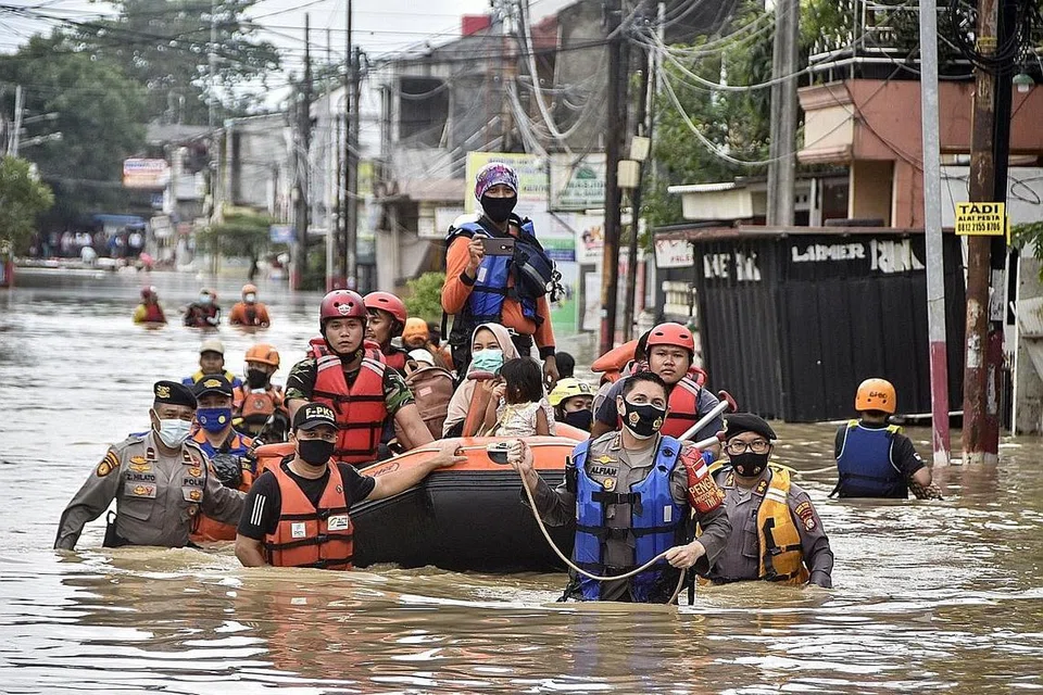 PENDUDUK DIBANTU: Pekerja penyelamat memindahkan penduduk daripada rumah mereka yang dilanda banjir di Bekasi kelmarin, apabila hujan lebat menyebabkan banjir di bandar di pinggir Jakarta itu. - Foto AFP