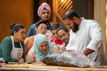 BANYAK TIMBA ILMU: Cik Tina Amin (bertudung) menganggap dapur ‘MasterChef Singapore’ sebagai dewan kuliah untuknya timba ilmu memasak dan mengenali bahan masakan.