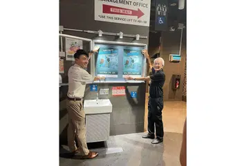 KEMPEN TANDAS AWAM BERSIH: Encik Baey (kiri) dan Encik D'Silva memasang poster Kempen Tandas Awam Bersih NEA 2022 dekat tandas awam di Pusat Penjaja @ Our Tampines Hub sempena pelancaran kempen itu semalam. - Foto FACEBOOK MAJLIS KEBERSIHAN AWAM