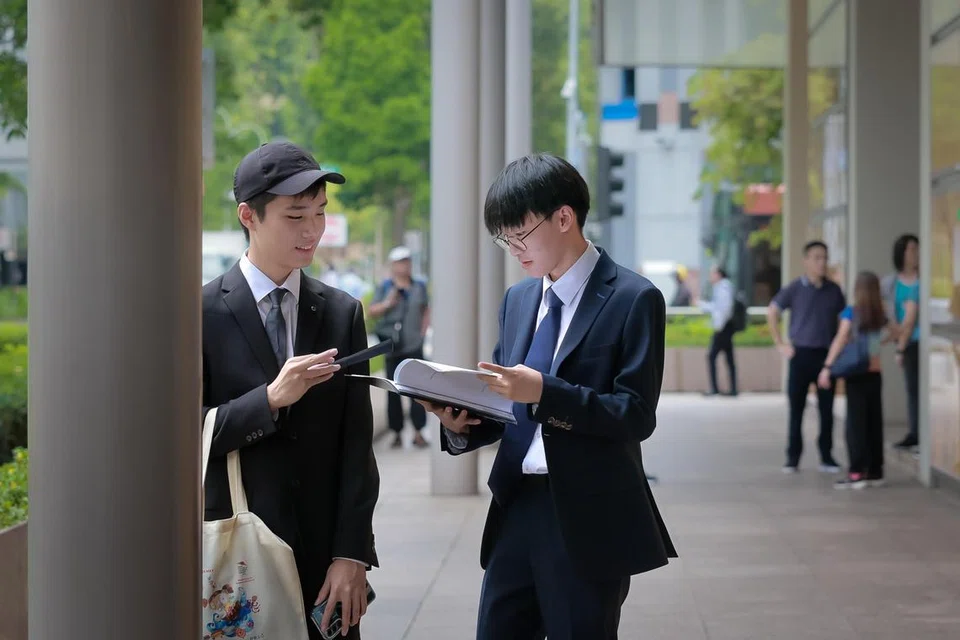 Pelajar Politeknik Ngee Ann, Gideon Soo (kiri) dan Issac Soh, siap berpakaian sut dan bertali leher untuk menghadiri prosiding keputusan hukuman bekas Menteri Pengangkutan, S. Iswaran, pada 3 Oktober.