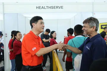 BANTUAN DIPERTINGKAT: Timbalan Setiausaha Agung NTUC, Encik Heng Chee How, berinteraksi bersama seorang pekerja migran semasa acara pesta sambutan Hari Pekerja bagi pekerja migran di Pusat Rekreasi MWC pada Ahad.