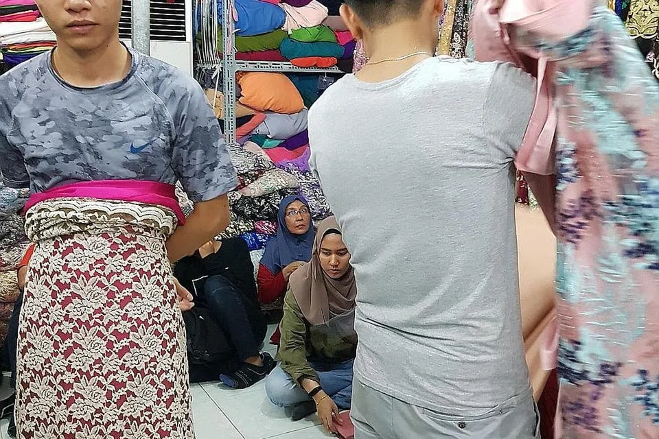 JANGAN TAK BELI, KAK: Encik Anh Dung (kiri) memperagakan kain renda Vietnam, antara ratusan jenis kain yang dipamerkan di Danny's Shop, luar kawasan Ho Chi Minh City. - Foto BH oleh NIZAM ISMAIL 