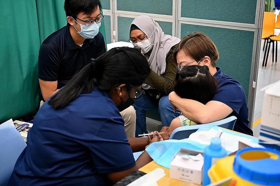 SOKONGAN SEMASA SUNTIKAN: Cik Nurhayati Rosli menemani anaknya, Nur Izara Il'Aisyah, enam tahun, yang sedang mendapatkan suntikan vaksinasi Covid-19 di Sekolah Katong APSN semalam. - Foto BH oleh LIM YAOHUI
