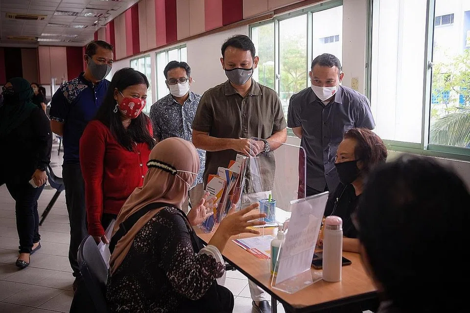 BANTU USAHA MENCARI KERJA: (Dari kiri) Encik Azriman Mansor dari M³@Marsiling-Yew Tee; anggota Pasukan Bertindak Bidang Tumpuan Empat mengenai Pekerjaan dan Daya Kerja M³ dan AP GRC Sembawang, Cik Mariam Jaafar; Pengarah Eksekutif Mendaki Sense, Encik Faiz Selamat; Encik Zaqy Mohamad; dan Mayor CDC South East dan anggota Pasukan Bertindak Bidang Tumpuan Empat mengenai Pekerjaan dan Daya Kerja M³, Encik Mohd Fahmi Aliman, beramah dengan seorang wanita yang mengunjungi Pameran Kerjaya 'Jump' di Kelab Masyarakat Marsiling semalam. - Foto BH oleh MARK CHEONG