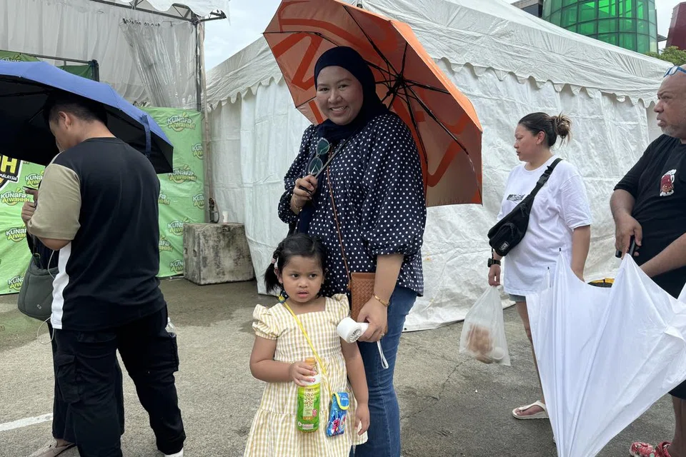 Cik Natasha Asyura (tengah, berpayung jingga) bersama anak perempuannya, telah menunggu dua jam untuk membeli ‘kunafa’ semasa ditemui Berita Harian di ‘Absolut Food Fest’. Beliau bergilir-gilir berdiri untuk beratur bersama suaminya (tiada dalam gambar). 