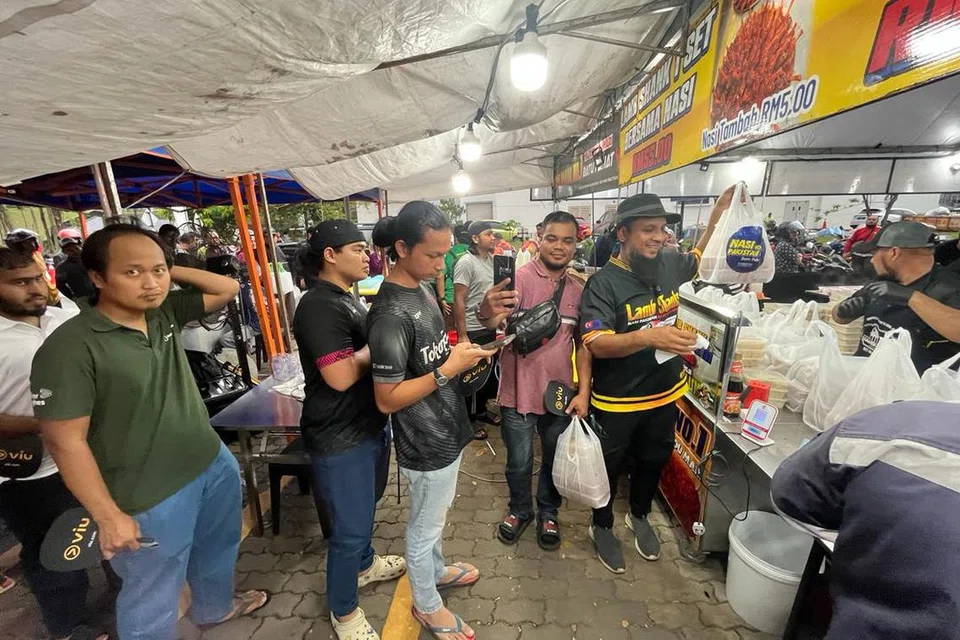 Pengusaha Nasi Pakistan No 1 Batu Pahat, Johor, Encik Azrul Hisham Basherahil (dua dari kanan), sibuk melayan pelanggan di bazar di Shah Alam, Selangor, sepanjang Ramadan.