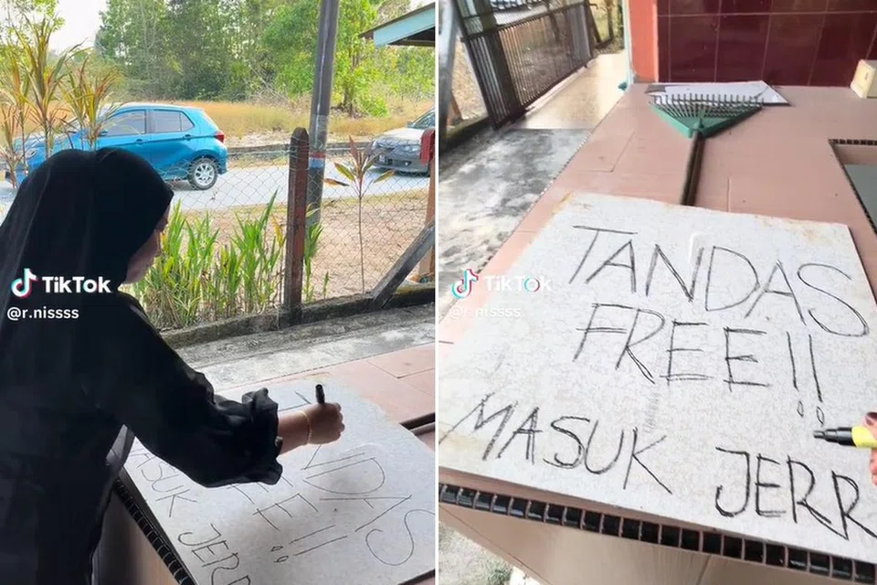 Cik Siti Noranis kelihatan menyediakan sepanduk tandas percuma yang kemudian diletak di luar rumahnya sementara kelihatan jalan raya di luar rumahnya sesak.