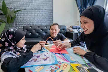 LIBATKAN DIRI: (Dari kanan) Cik Zinnur’Ain Rabu dan suaminya, Muhammad Fitri Sulaiman, menggunakan cara  ‘gentle parenting’ ketika mengajar anak perempuannya, Putri Mahirah Ariqah Muhammad Fitri, Matematik.