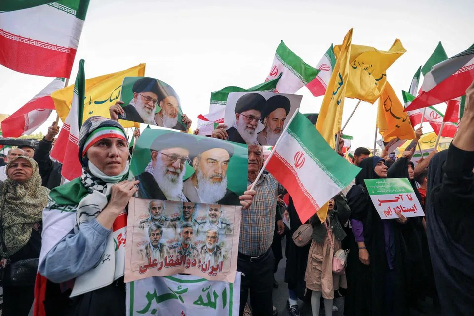 Seorang wanita Iran memegang poster yang memaparkan potret pemimpin tertinggi Iran, Ayatollah Ali Khamenei (kiri), dan bekas pemimpin tertinggi, Ayatollah Ruhollah Khomeini, ketika orang ramai meraikan gencatan senjata antara Iran dengan Israel di Dataran Enghelab, ibu negara Teheran, pada 24 Jun 2025. 