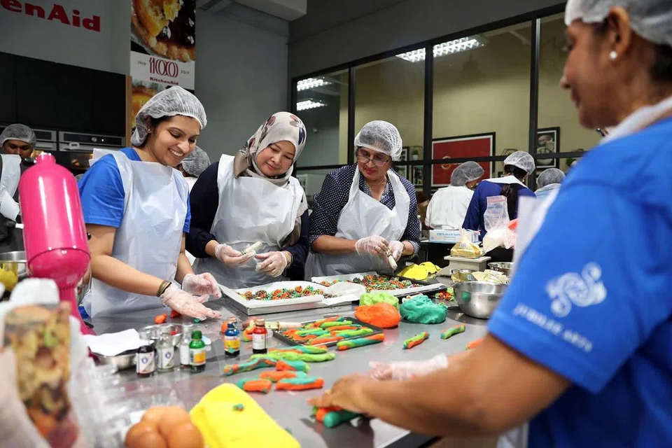 (Dari kiri) Cik Natasha Amin Mohammad, Cik Zainon Haron dan Cik Nazlin Sultananli Jinah membuat kuih untuk diagihkan kepada para penerima sebelum Hari Raya nanti. FOTO: GIN TAY