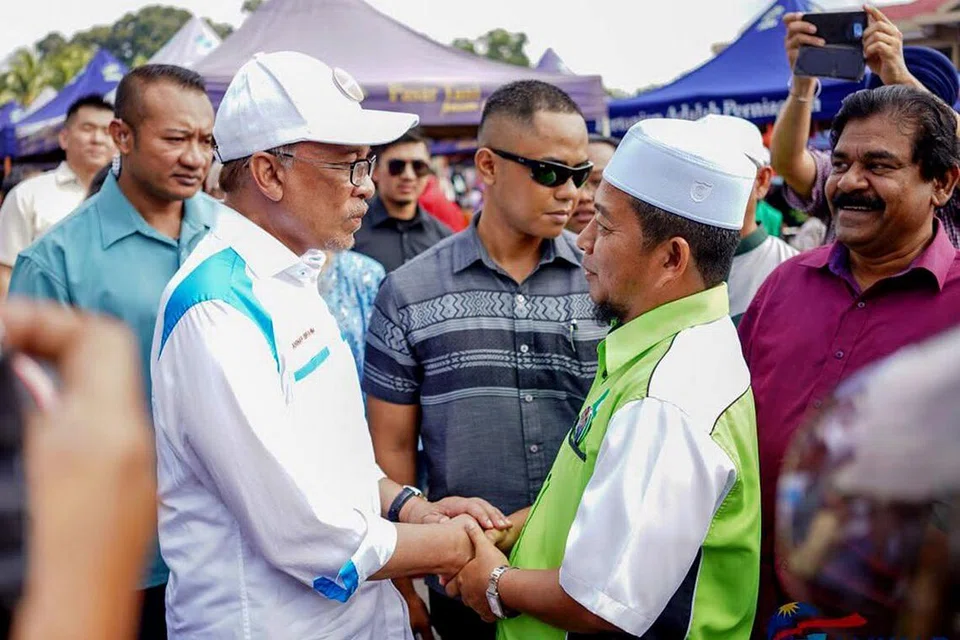 GIAT BERKEMPEN: Datuk Anwar (dua dari kiri) sedang menjalankan kempennya menemui penduduk di kawasan Pasar Tani Batu 4, Bagan Pinang, Port Dickson. - Foto TWITTER