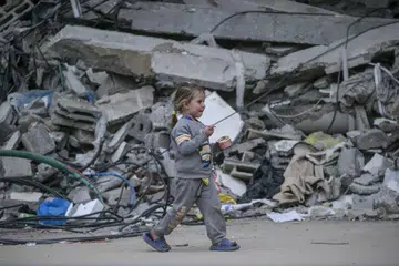 Seorang kanak-kanak Palestin dilihat berjalan sambil memakan aiskrim ketika melarikan diri daripada serangan udara Israel di Bandar Gaza pada 1 April.
