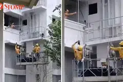 SEKAT KERJA: Seorang lelaki kelihatan menggunakan galah untuk menghalang pekerja menjalankan kerja pemasangan jaring di sebuah blok di Fernvale, Sengkang.