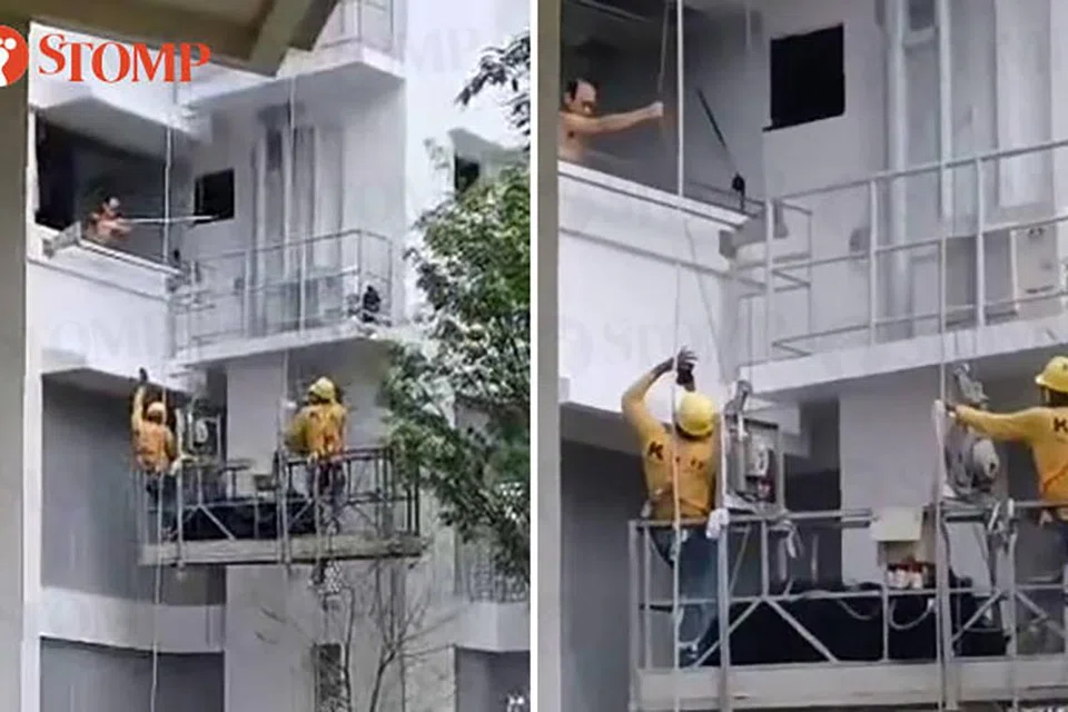 SEKAT KERJA: Seorang lelaki kelihatan menggunakan galah untuk menghalang pekerja menjalankan kerja pemasangan jaring di sebuah blok di Fernvale, Sengkang.