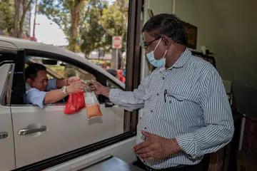 KONSEP MENYEGARKAN: Encik Shajahan Mohamad Yakoob melayan pelanggan Encik Zairi, 51 tahun, yang membeli teh tarik melalui kaedah pandu lalu di Akbar 24 Hours Restaurant, di kawasan Tanjong Pagar.