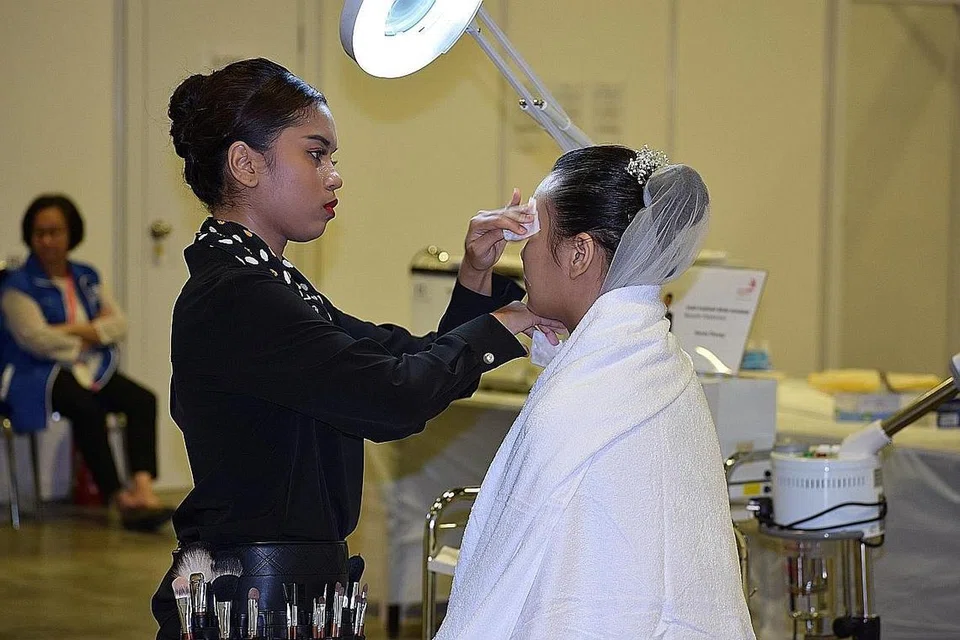 MINAT BIDANG SOLEKAN: Cik Izzah Irsalinah Jumahat (kiri) menunjukkan kebolehannya dalam bidang solekan di WorldSkills Singapore (WSS) 2018 awal Julai lalu. - Foto POLITEKNIK REPUBLIC