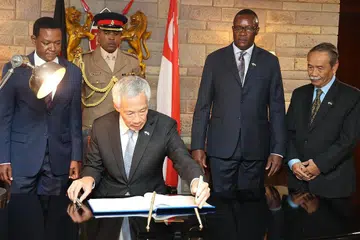 TANDATANGAN BUKU TETAMU: Encik Lee Hsien Loong menandatangani buku tetamu di lapangan terbang Jomo Kenyatta sejurus tiba di Nairobi, ibu kota Kenya. Turut berada di situ ialah Encik Yatiman Yusof (kanan), Duta Bukan Pemastautin Singapura ke Kenya. - Foto ZAOBAO